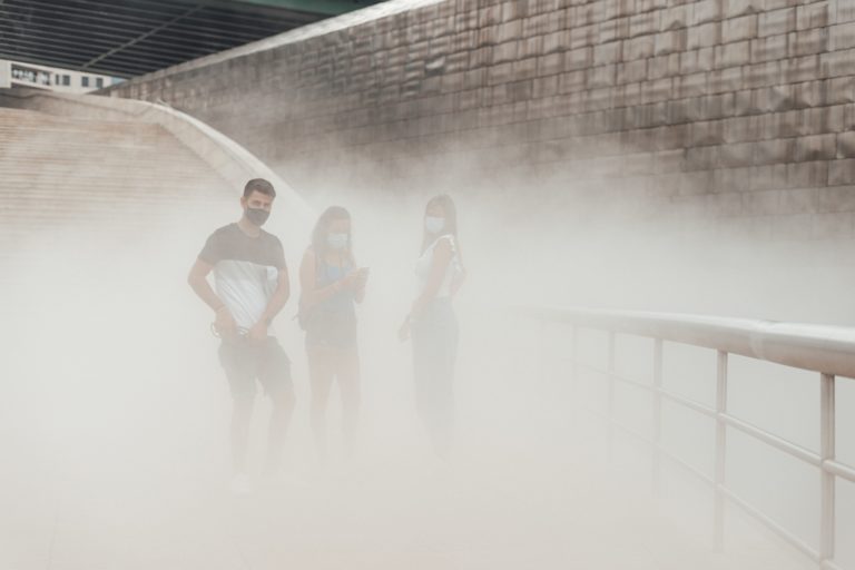 Three people with masks on a pollution cloud